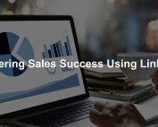 Laptop displaying graphs and charts related to mastering B2B sales success using LinkedIn, with a person holding a coffee cup in a professional setting.